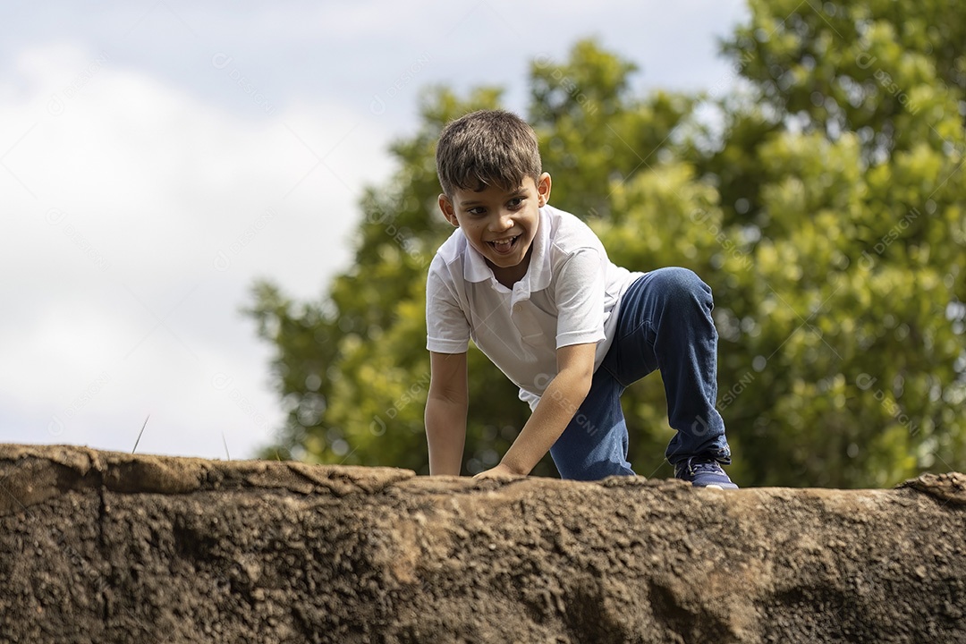 Menino de jeans azul e camiseta branca se divertindo ao ar livre