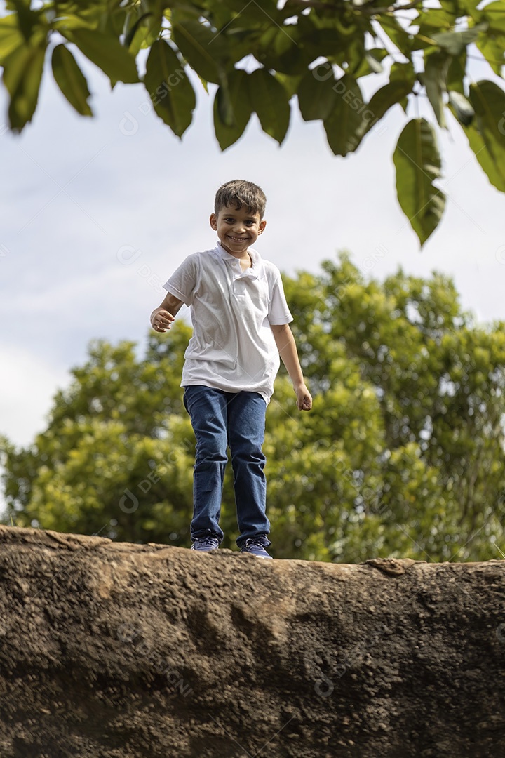 Menino de jeans azul e camiseta branca se divertindo ao ar livre