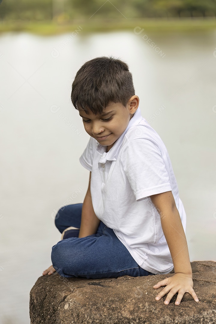 Menino de jeans azul e camiseta branca se divertindo ao ar livre