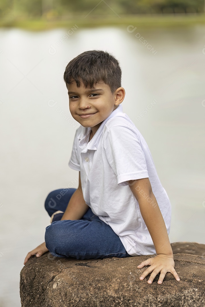 Menino de jeans azul e camiseta branca se divertindo ao ar livre