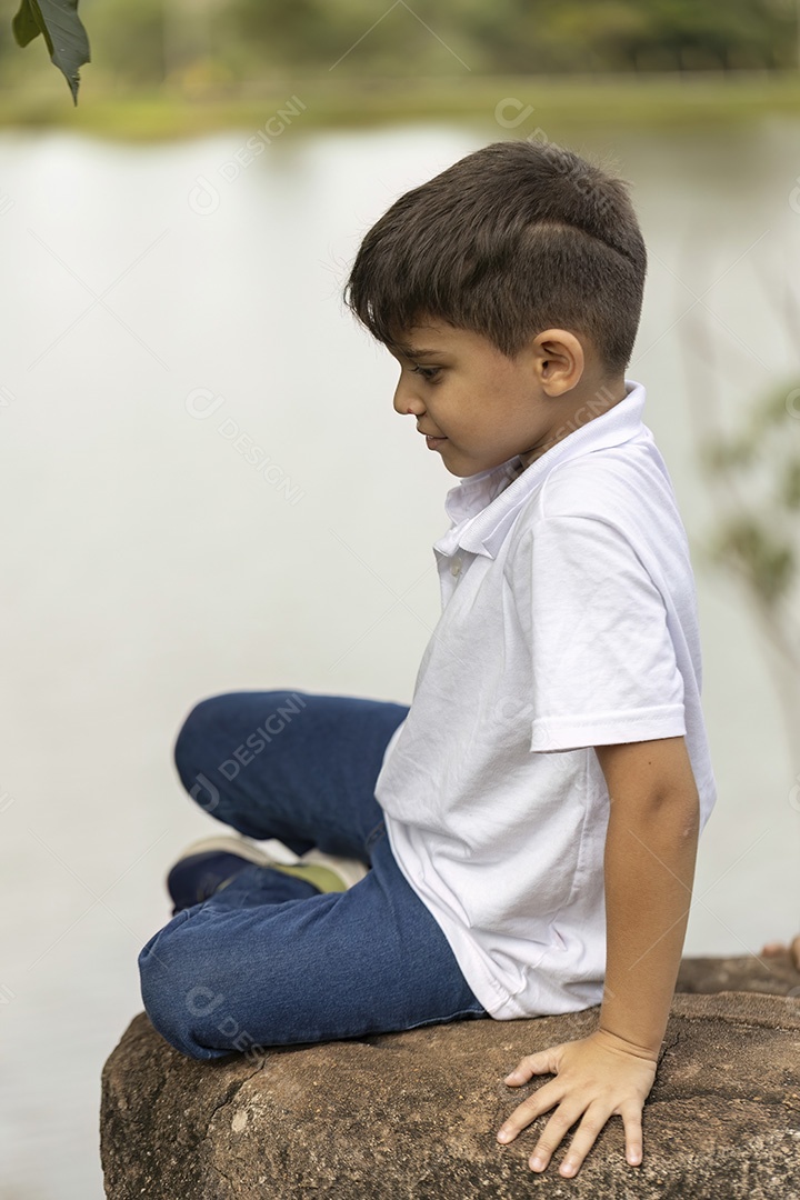 Menino de jeans azul e camiseta branca se divertindo ao ar livre