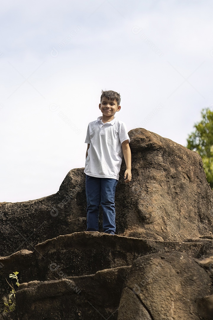 Menino de jeans azul e camiseta branca se divertindo ao ar livre