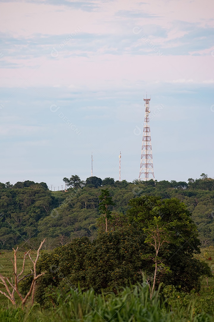 Torre de telecomunicações de metal no topo de uma cordilheira no meio da selva ao pôr do sol