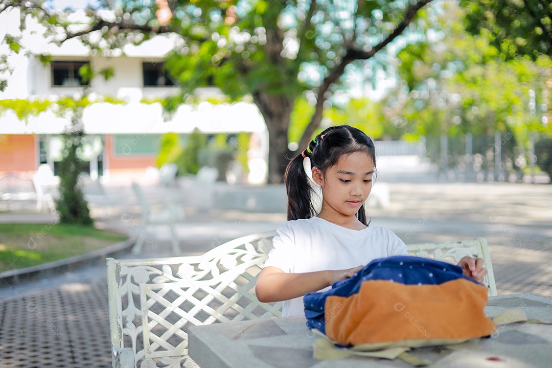 Menina asiática lendo um livro depois das aulas aprendendo lição de casa