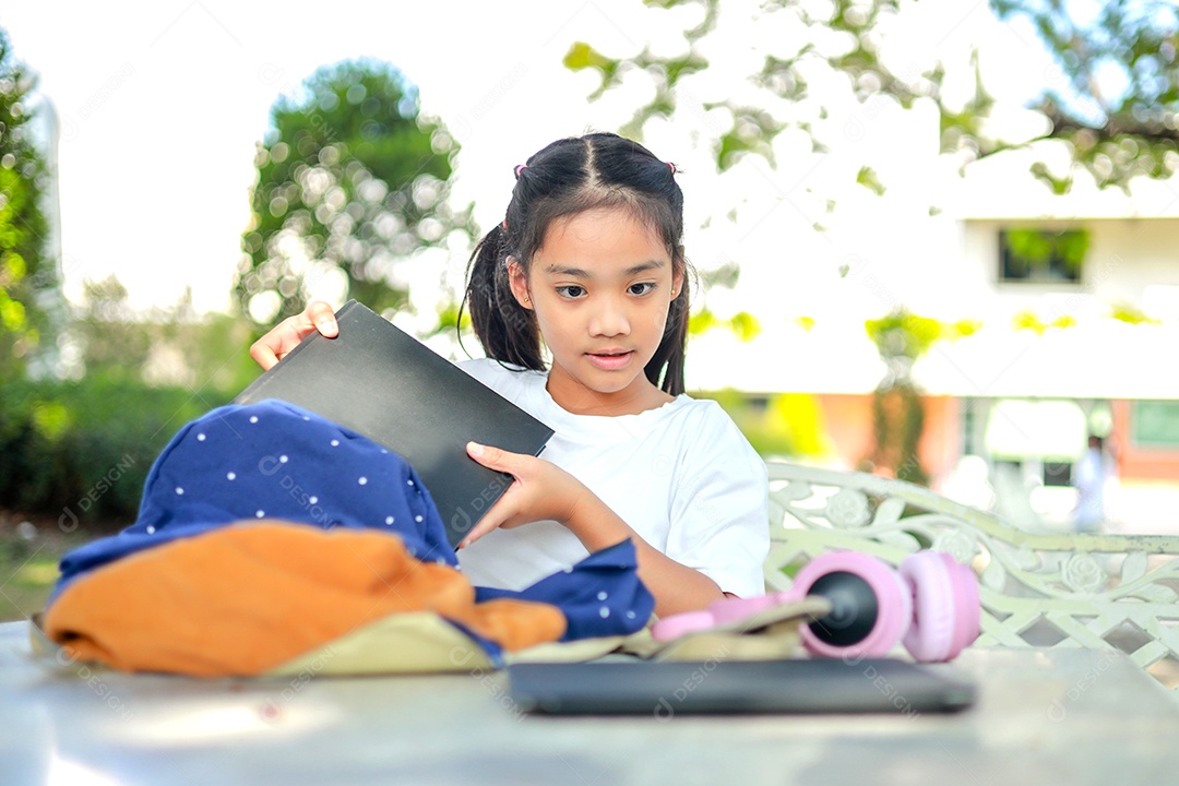 Menina asiática lendo um livro depois das aulas aprendendo lição de casa