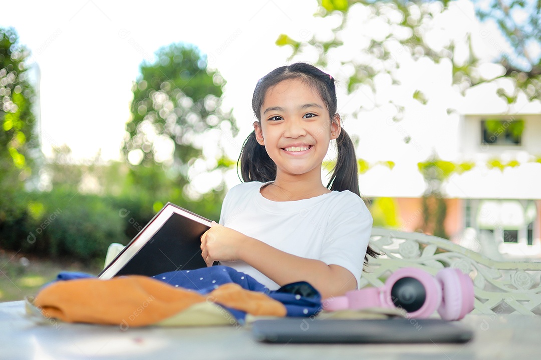 Menina asiática lendo um livro depois das aulas aprendendo lição de casa