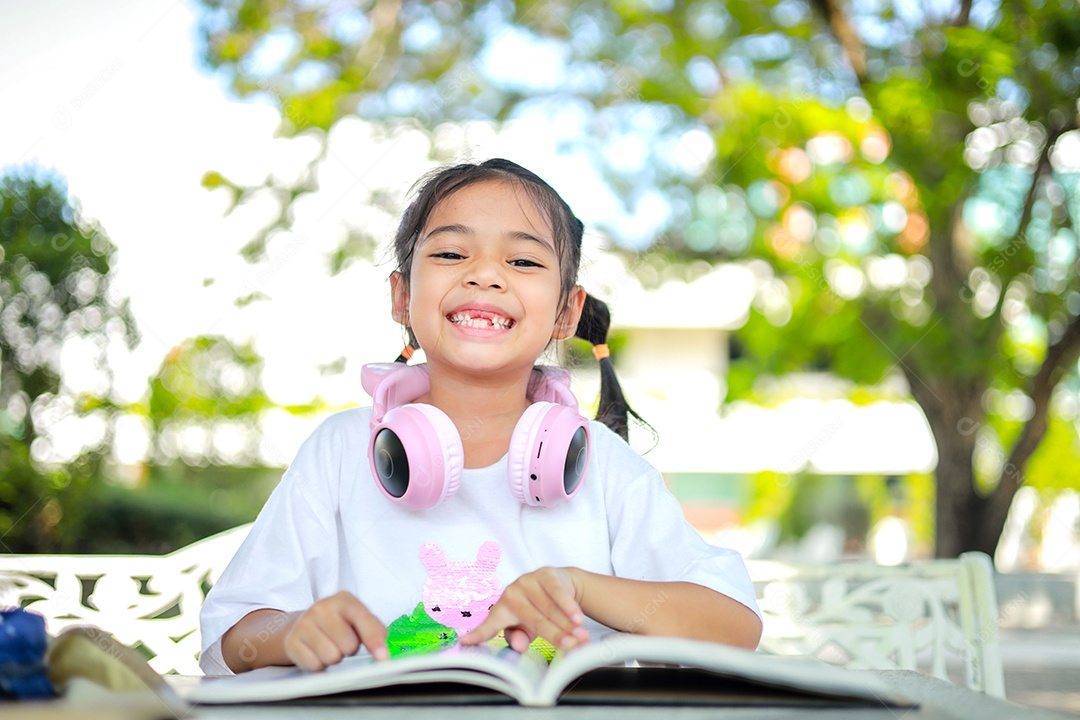 Menina asiática lendo um livro depois das aulas aprendendo lição de casa