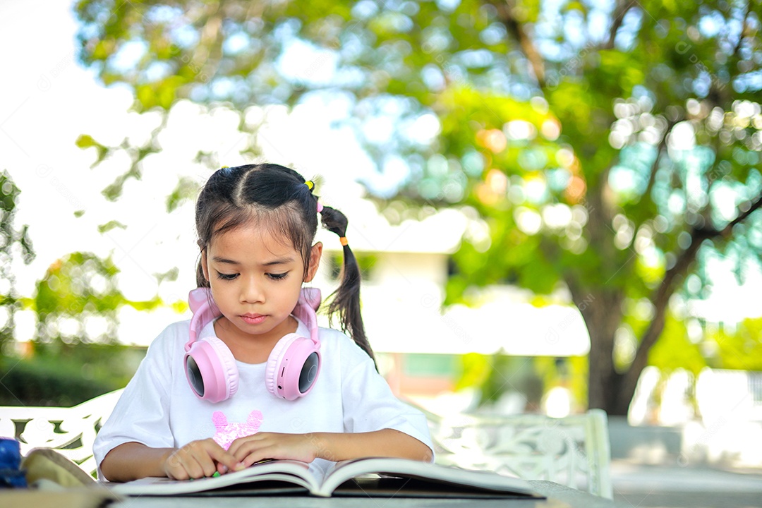 Menina asiática lendo um livro depois das aulas aprendendo lição de casa