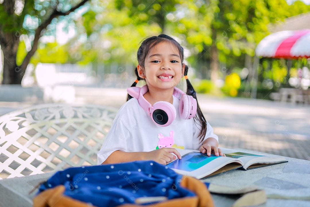 Menina asiática lendo um livro depois das aulas aprendendo lição de casa