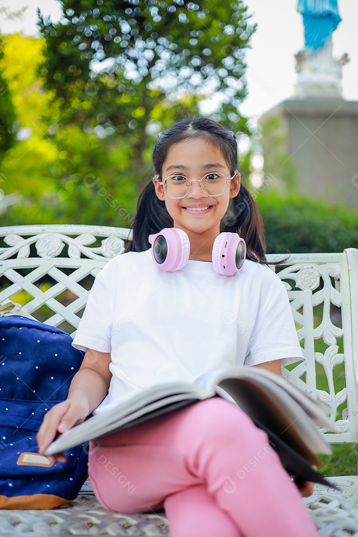 Menina asiática lendo um livro depois das aulas aprendendo lição de casa
