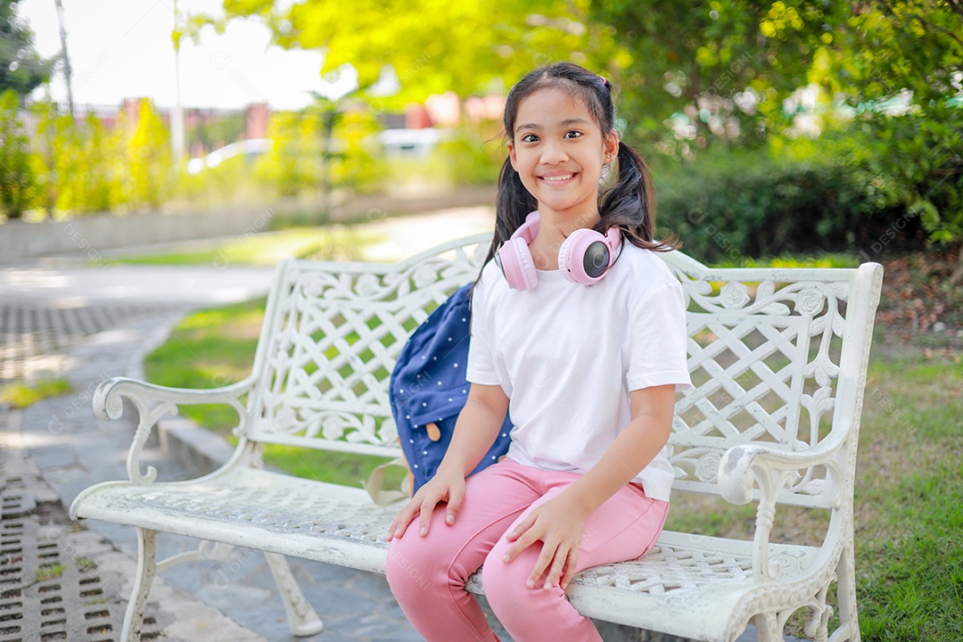 Menina asiática sentada em uma cadeira branca na escola se sente feliz e gosta de voltar para a escola.