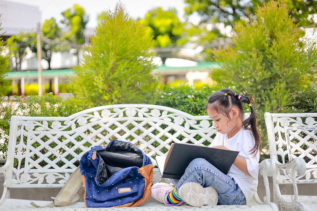 Menina asiática lendo um livro depois das aulas aprendendo lição de casa