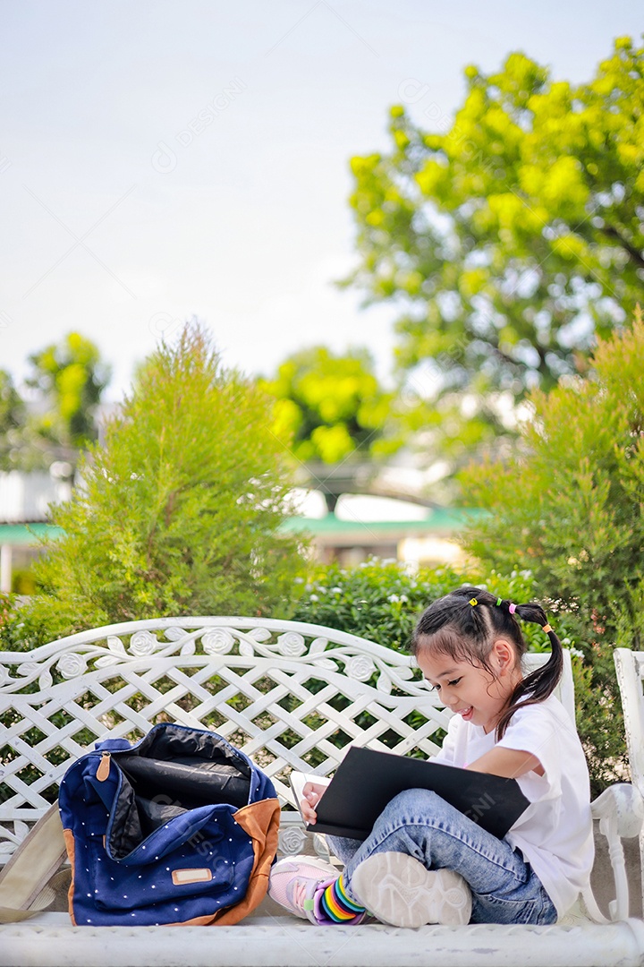 Menina asiática lendo um livro depois das aulas aprendendo lição de casa