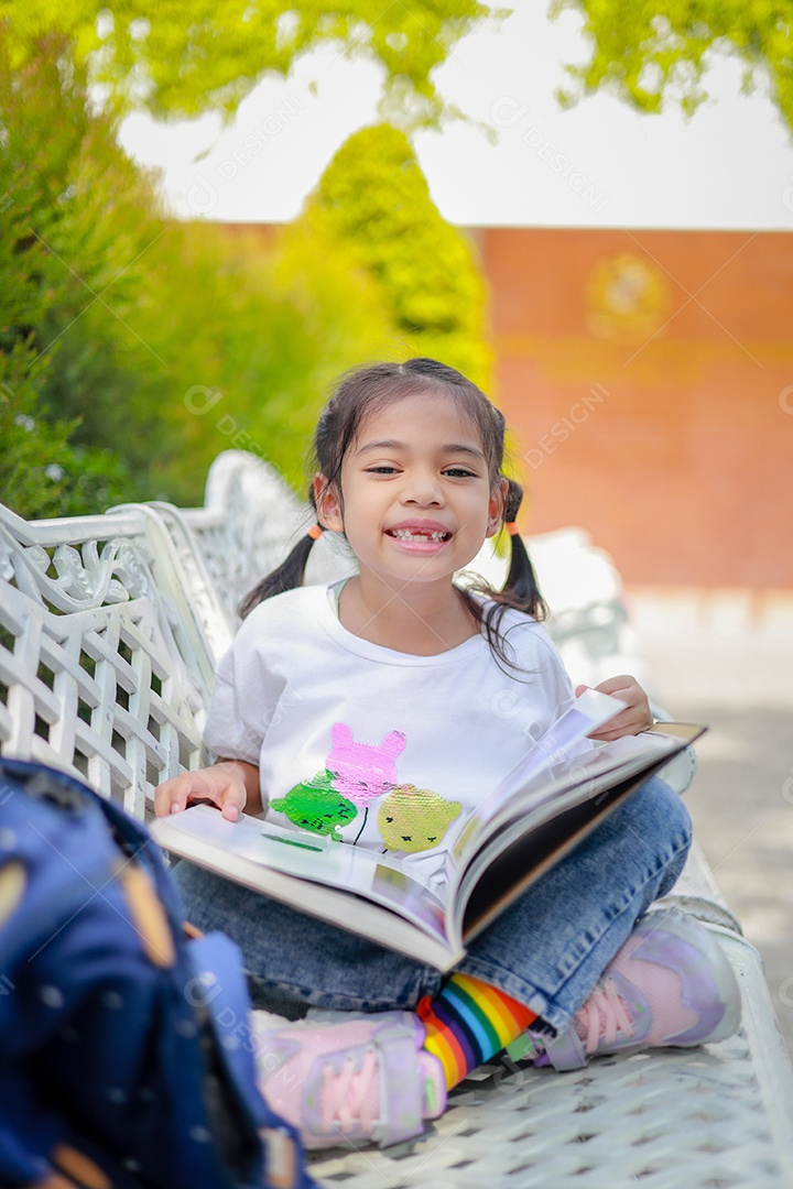 Menina asiática lendo um livro depois das aulas aprendendo lição de casa