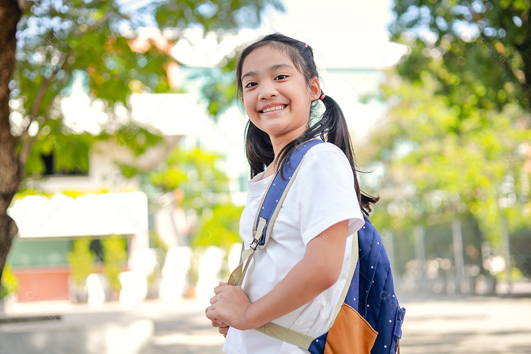 Criança menina asiática com uma mochila indo para a escola com diversão.