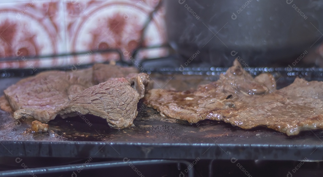 Conceito de churrasco em casa, carne sendo preparada em uma placa de fogão caseira