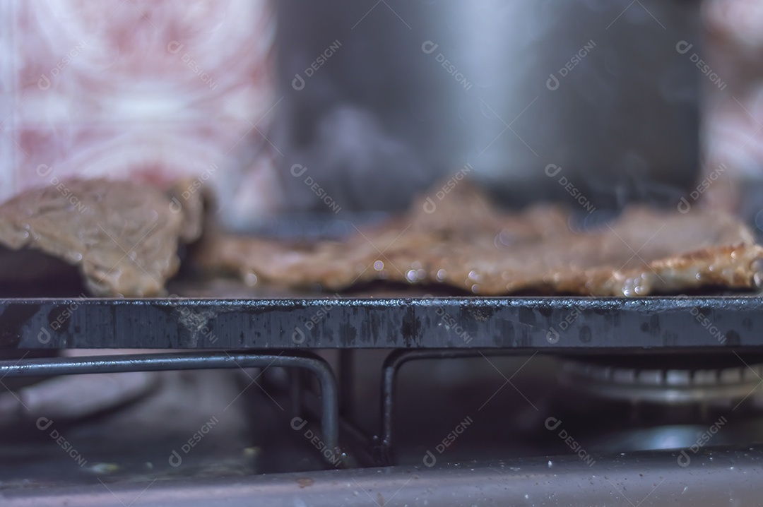 Conceito de churrasco em casa, carne sendo preparada em uma placa de fogão caseira