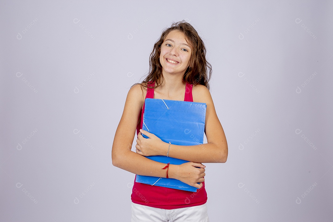 Linda menina jovem segurando material escolar sobre fundo isolado