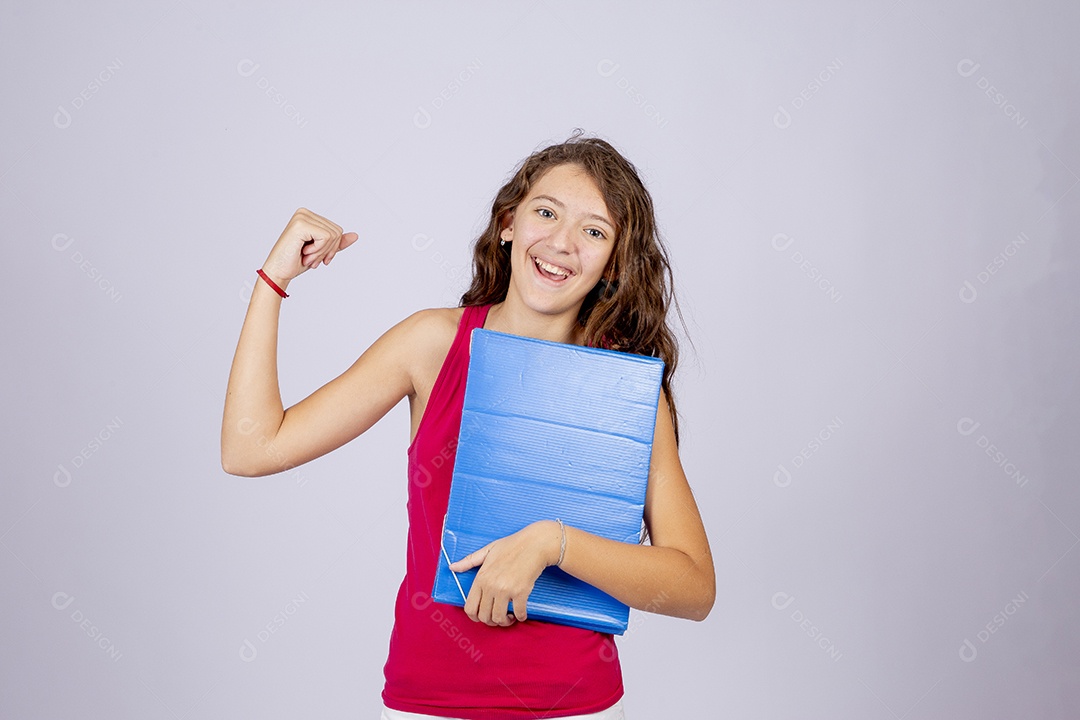 Linda menina jovem segurando material escolar sobre fundo isolado