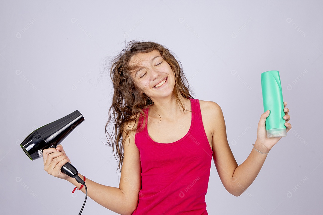 Linda menina jovem usando secador sobre fundo isolado