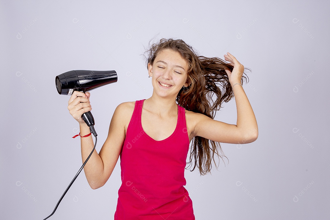 Linda menina jovem usando secador sobre fundo isolado