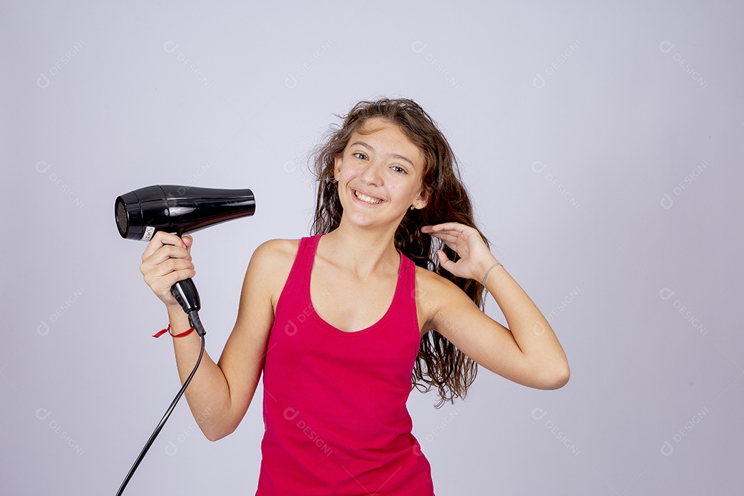 Linda menina jovem usando secador sobre fundo isolado