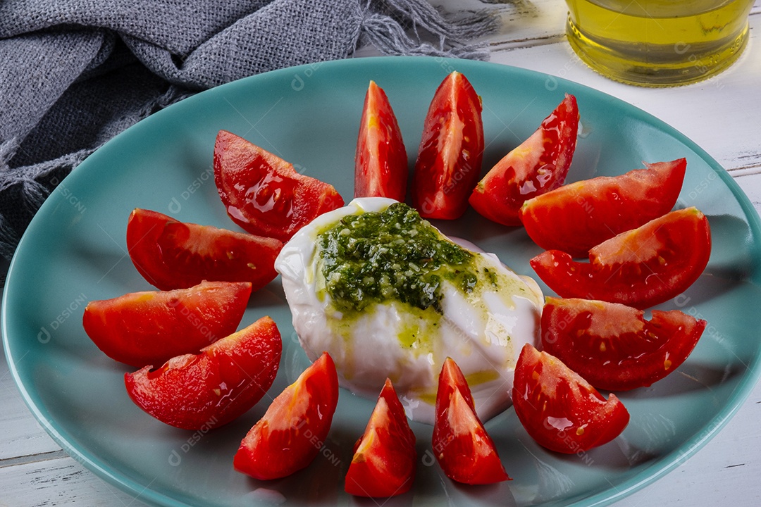 Mussarela de búfala burrata coberta com molho pesto e rodelas de tomate.