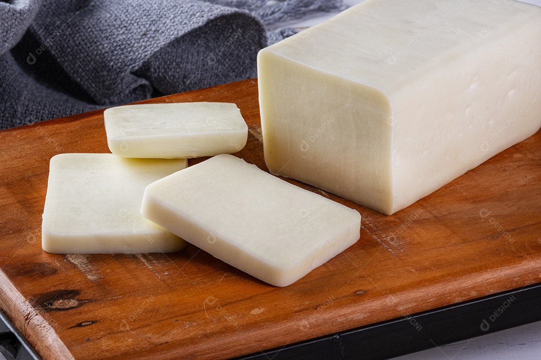 Barra de mussarela de búfala fatiada na placa de madeira.