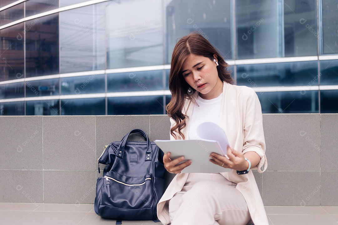 Bela jovem empresária sentada na escada e lendo um livro