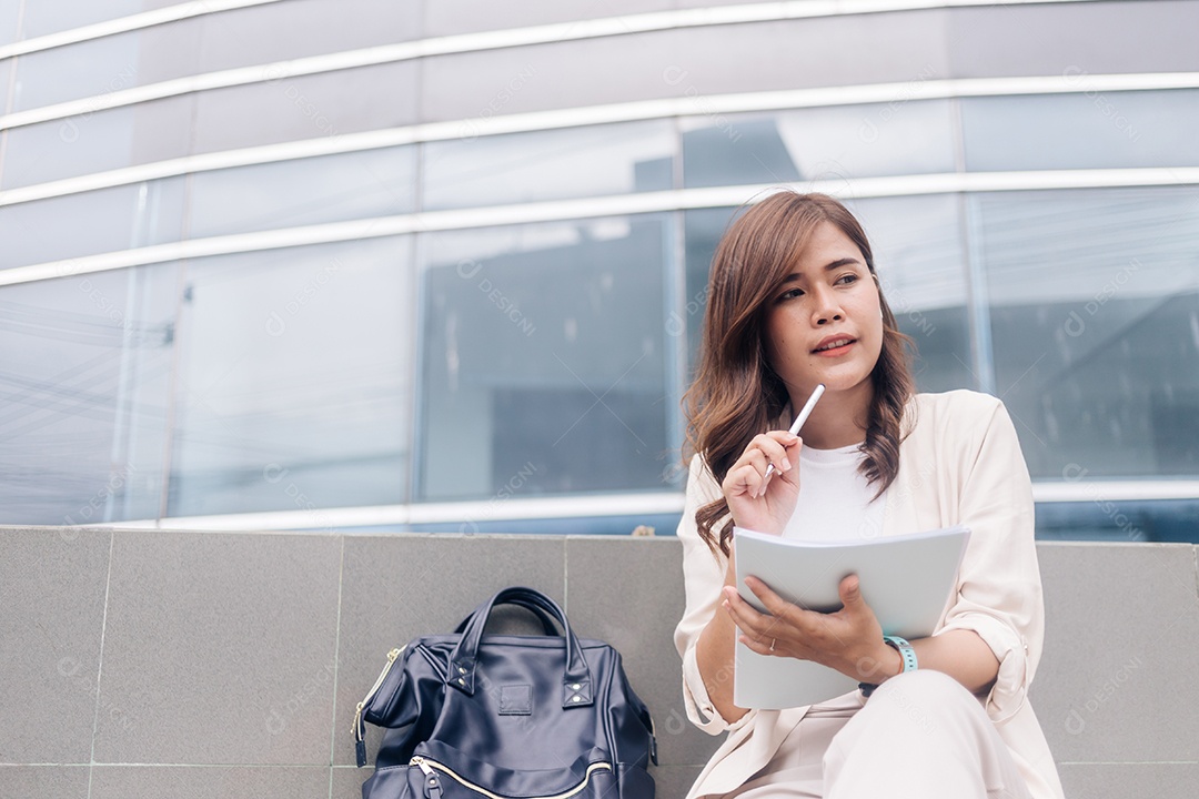 Atraente jovem empresária escrevendo no caderno enquanto está sentado na escada ao ar livre