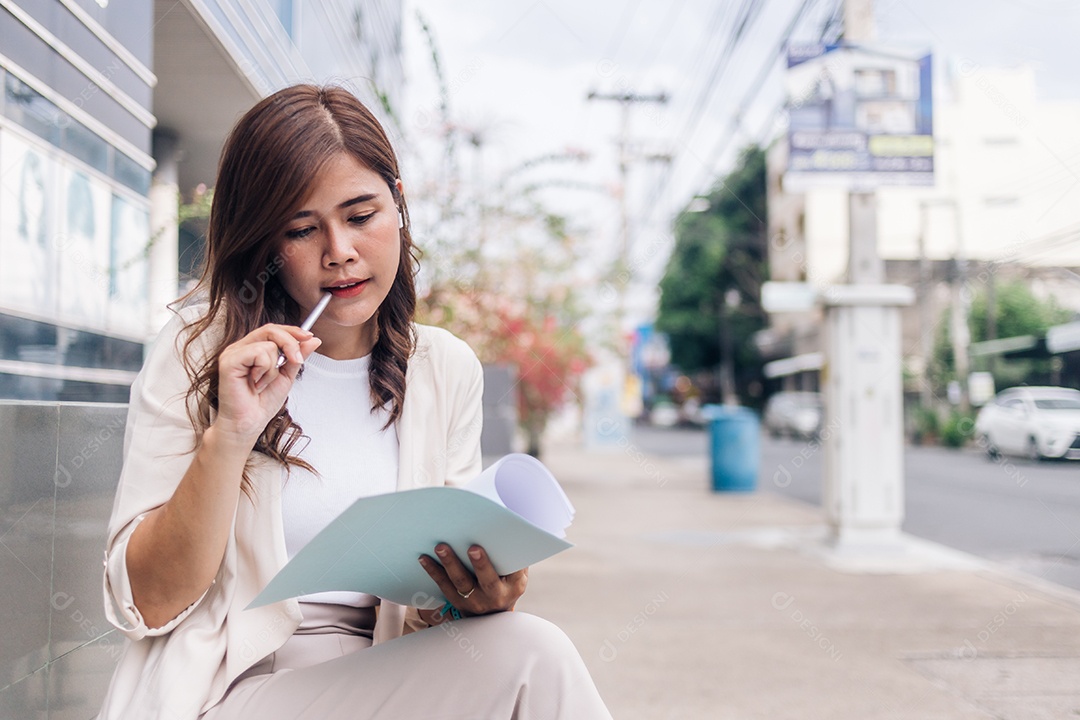 Atraente jovem empresária escrevendo no caderno enquanto está sentado na escada ao ar livre