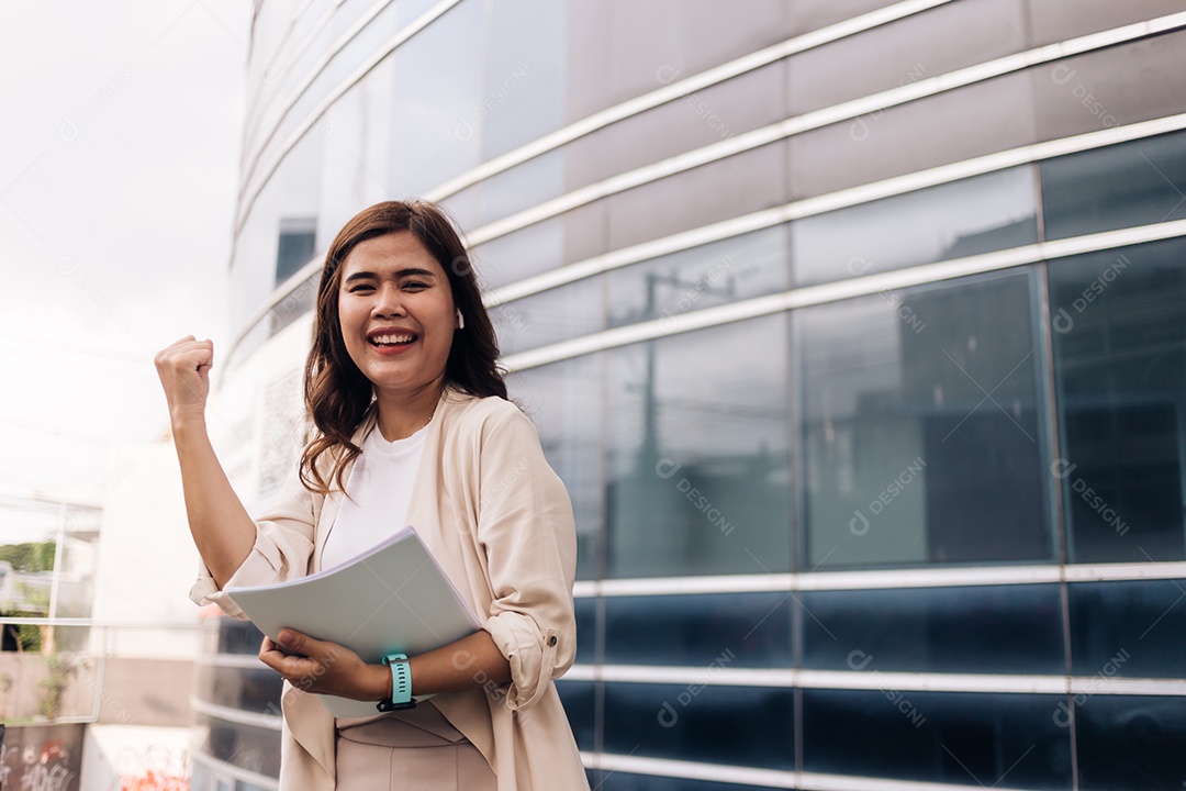 Empresária bem-sucedida em frente ao prédio de escritórios e segurando o documento.