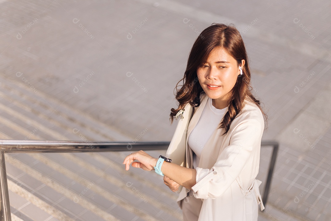 Bela empresária asiática usando relógio inteligente na cidade.