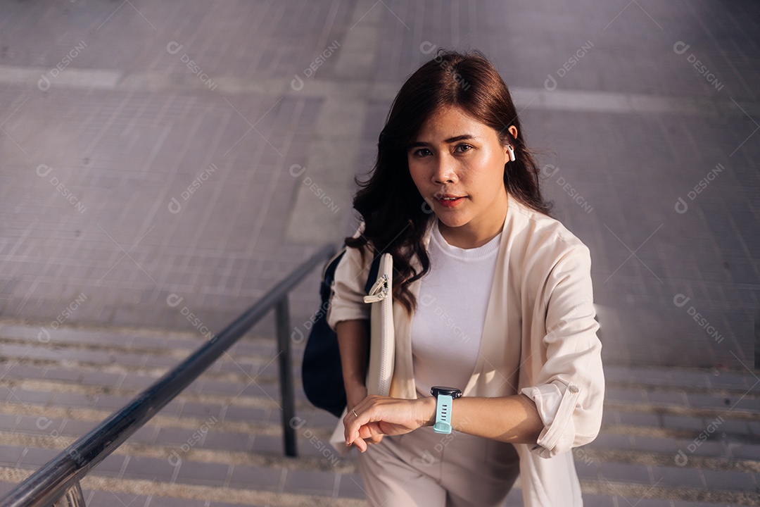 Bela empresária asiática usando relógio inteligente na cidade.