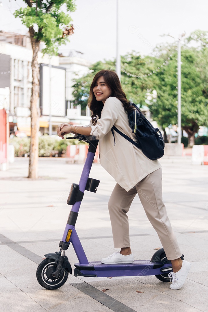 Retrato de jovem asiática andando de scooter elétrica no parque