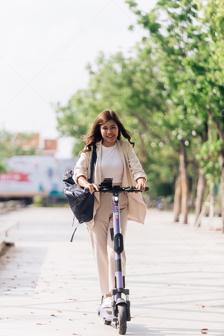 Retrato de jovem asiática andando de scooter elétrica no parque