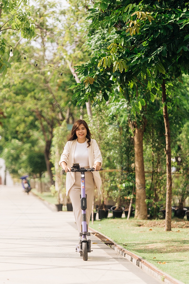 Retrato de jovem asiática andando de scooter elétrica no parque