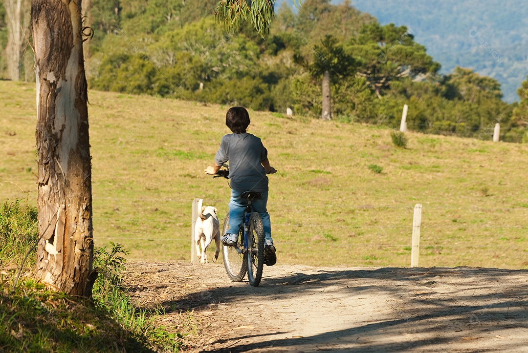 Menino andando de bicicleta na fazenda
