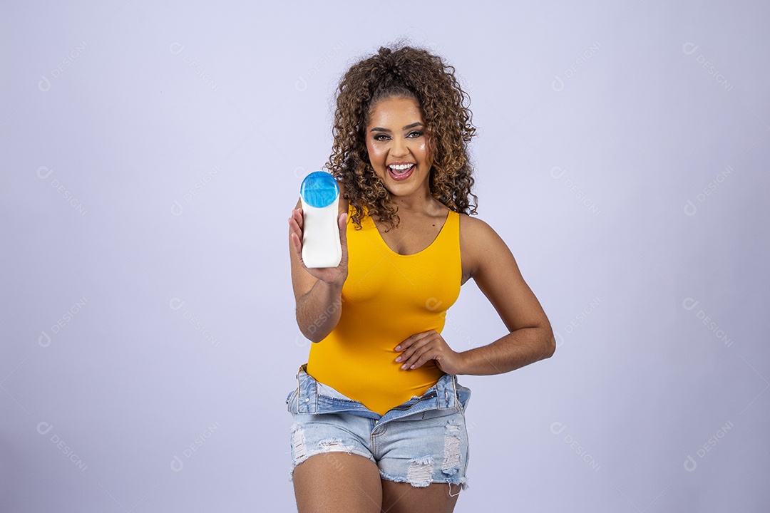Linda mulher de maiô amarelo segurando frasco de protetor solar em fundo branco