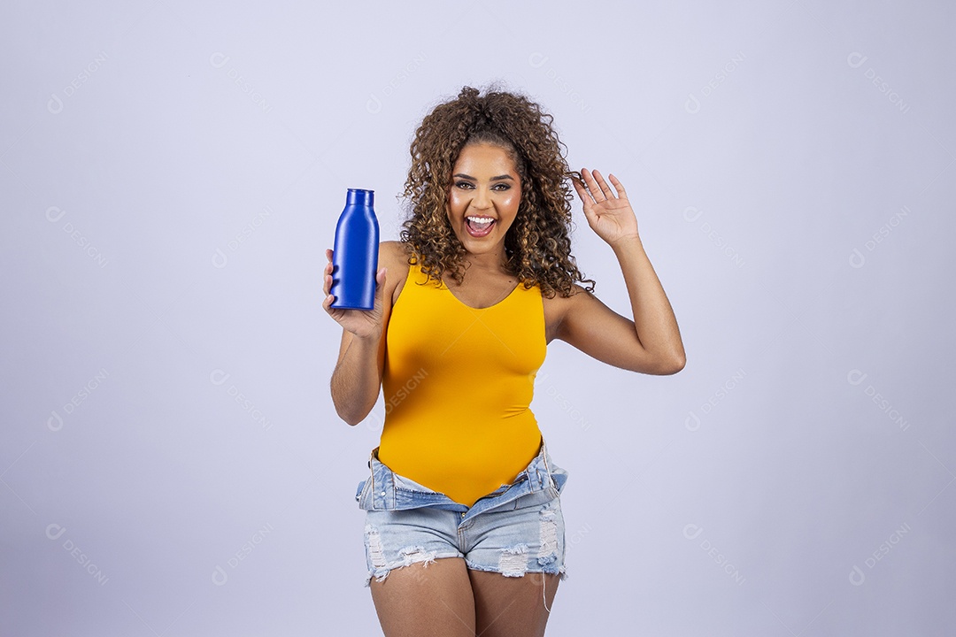 Linda mulher com maiô amarelo segurando frasco de hidratante corporal em fundo branco
