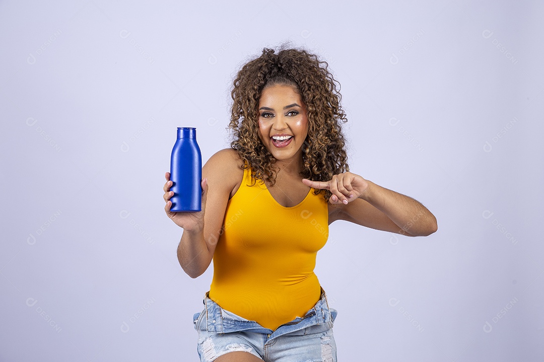 Linda mulher com maiô amarelo segurando frasco de hidratante corporal em fundo branco