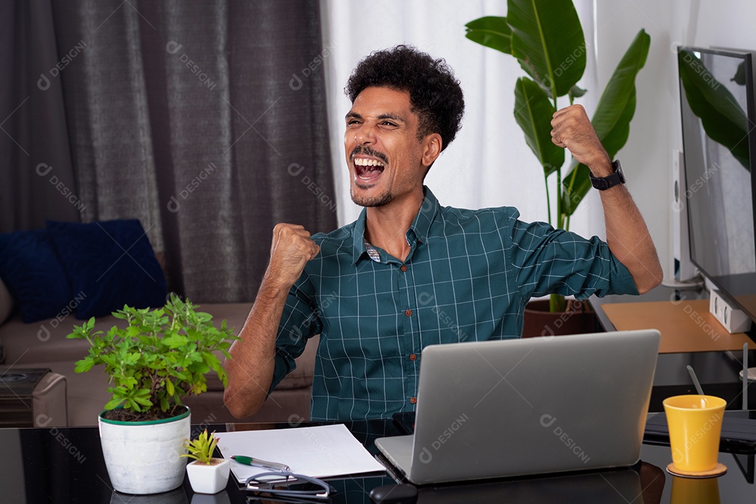 Jovem negro fazendo home office durante o dia na mesa com laptop