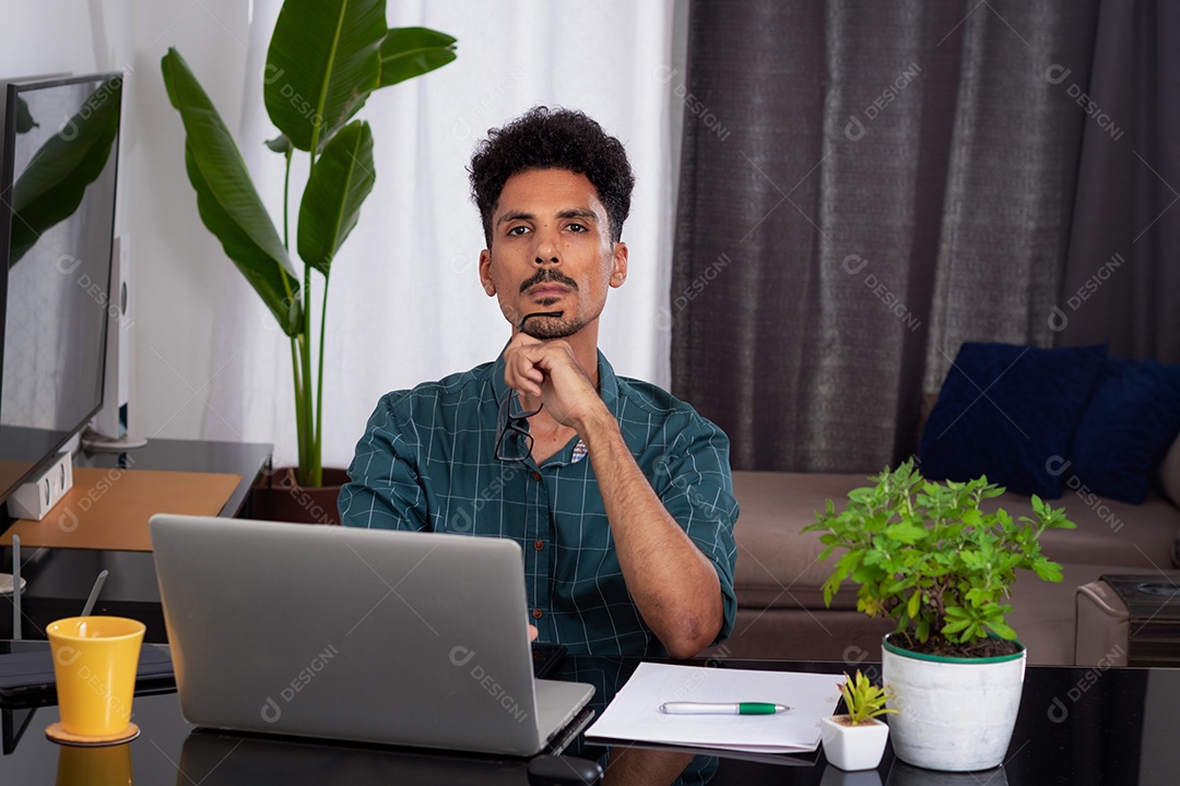 Jovem negro fazendo home office durante o dia na mesa com laptop