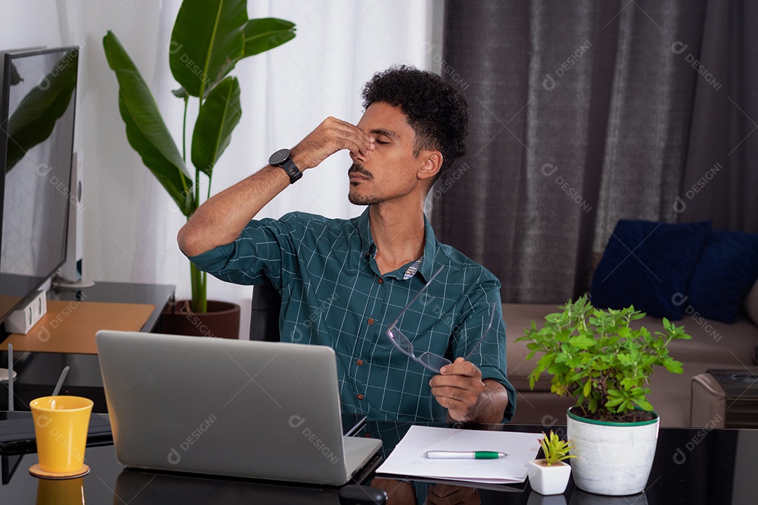 Jovem negro fazendo home office durante o dia na mesa com laptop