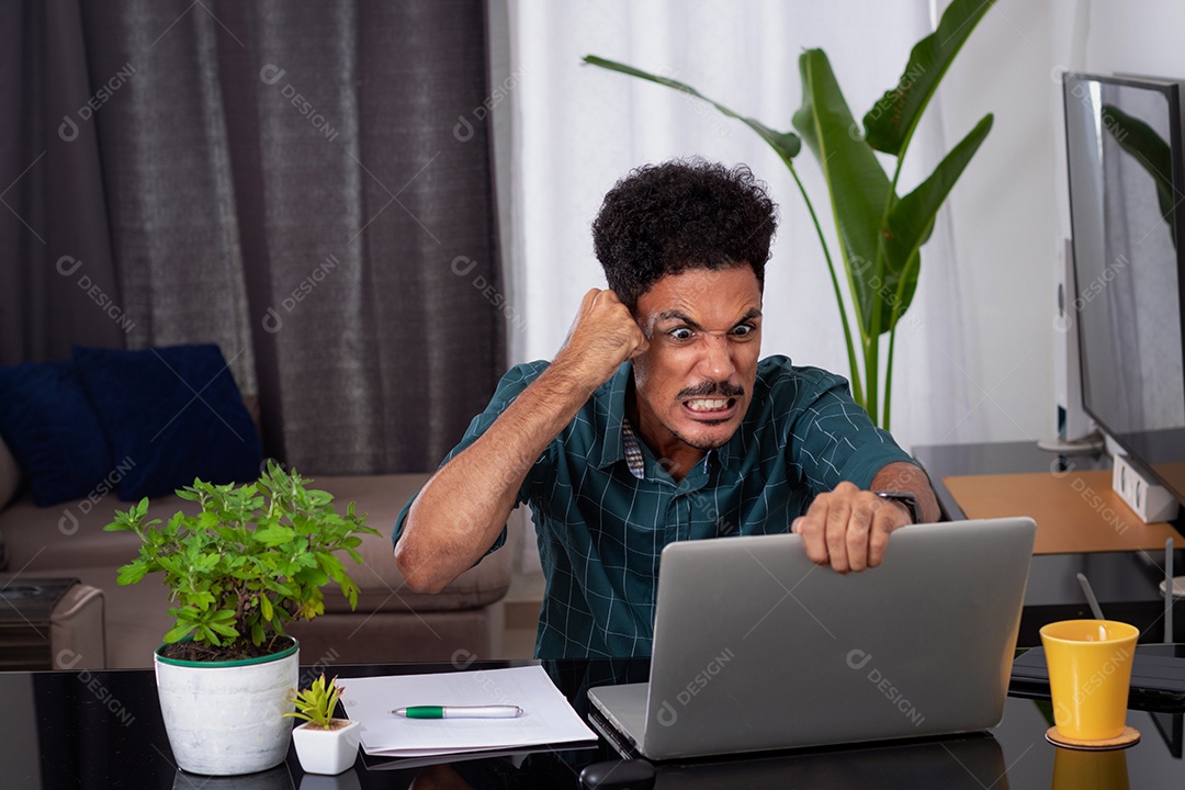Jovem negro fazendo home office durante o dia na mesa com laptop