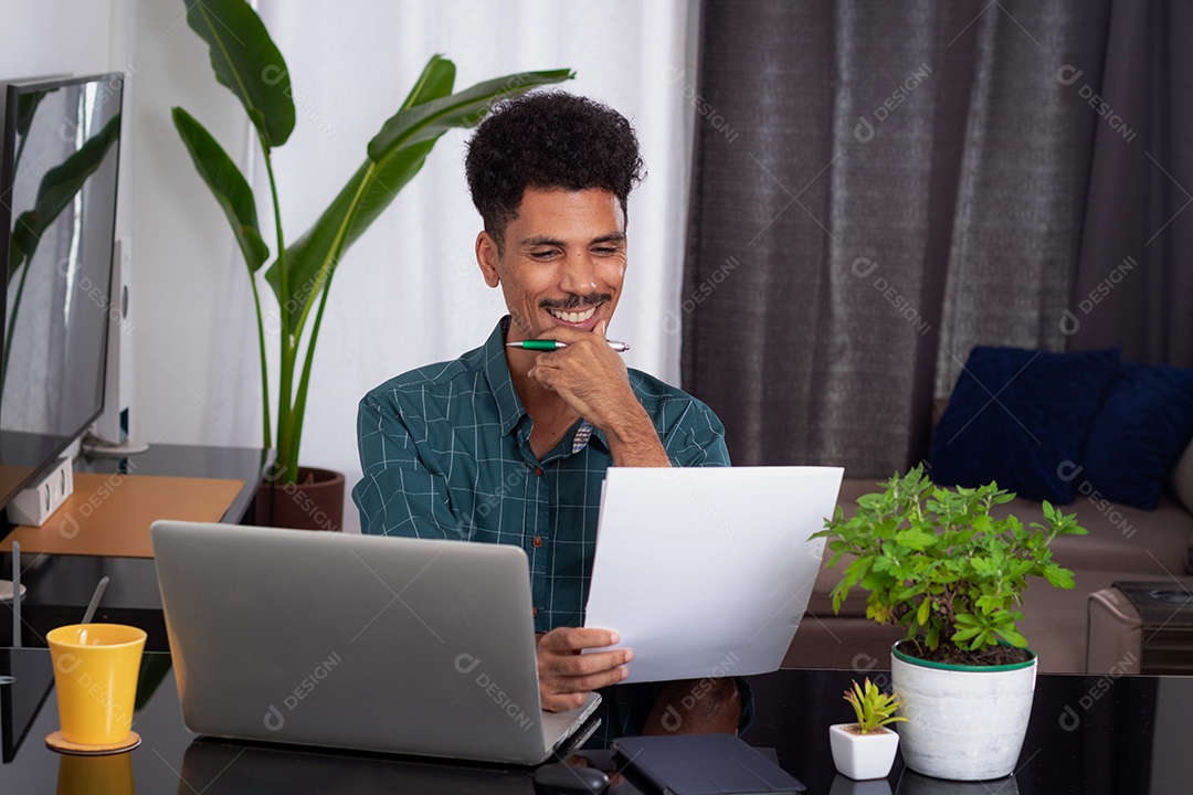 Jovem negro fazendo home office durante o dia na mesa com laptop
