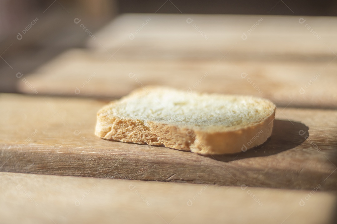 Pão em forma de torrada em uma superfície de madeira com luz natural.