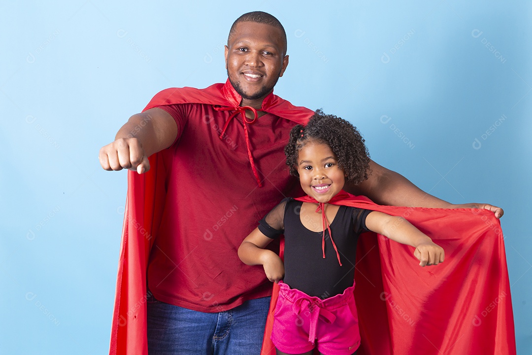 Pai e filha juntos com capa de super herói em fundo azul