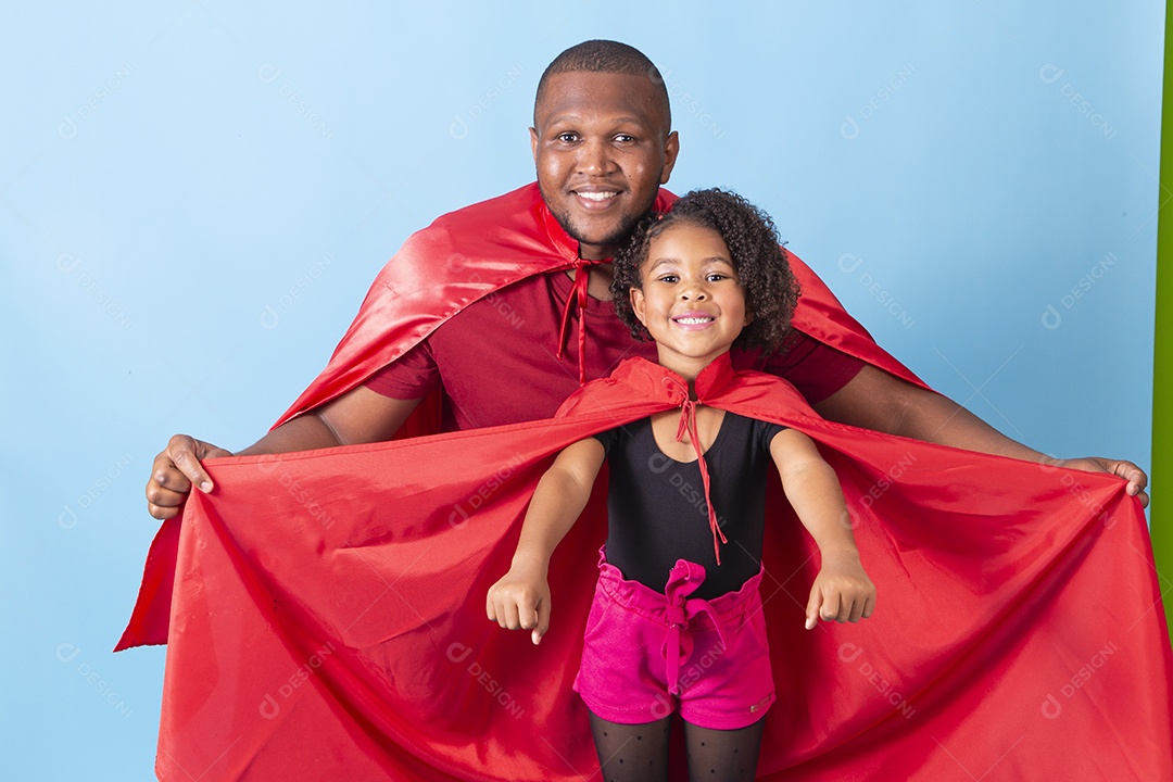 Pai e filha juntos com capa de super herói em fundo azul