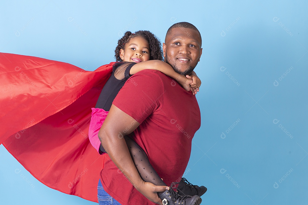 Pai e filha juntos com capa de super herói em fundo azul